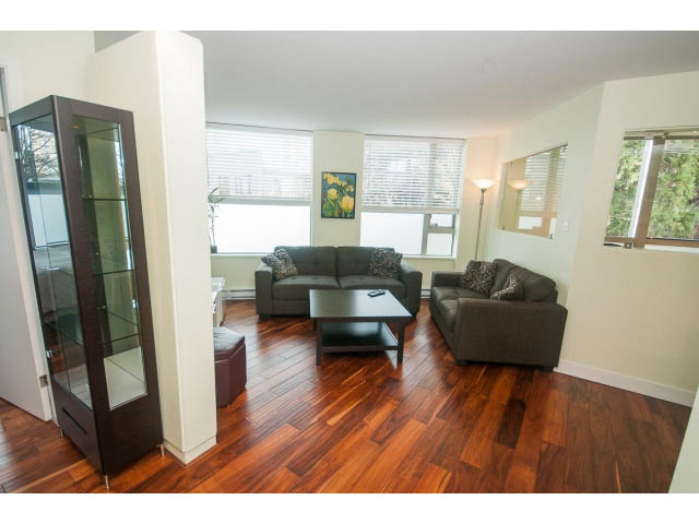 Furnished living room with hardwood floors and a glass display cabinet. - 202 - 1277 Nelson St, Vancouver Downtown