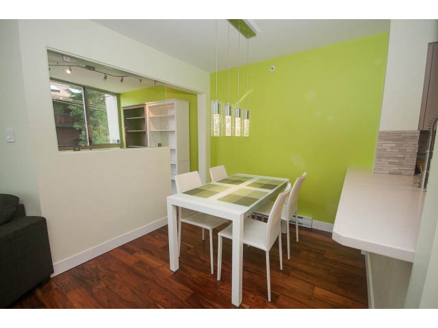 Furnished dining area with hardwood floors, green walls, and modern lighting. - 202 - 1277 Nelson St, Vancouver Downtown