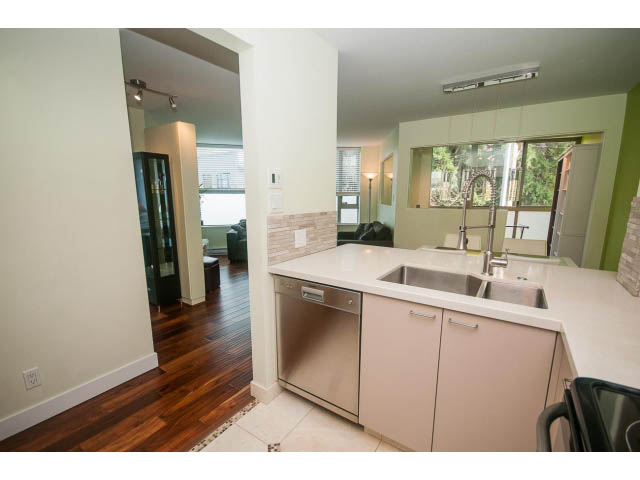 Bright kitchen with stainless steel sink, white countertops, hardwood floors, and a view of the city. - 202 - 1277 Nelson St, Vancouver Downtown