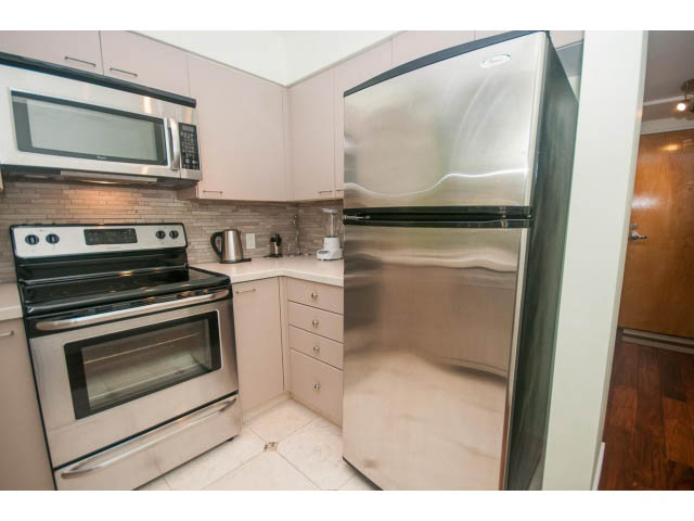 Bright kitchen with stainless steel appliances, white cabinets, and hardwood floors. - 202 - 1277 Nelson St, Vancouver Downtown