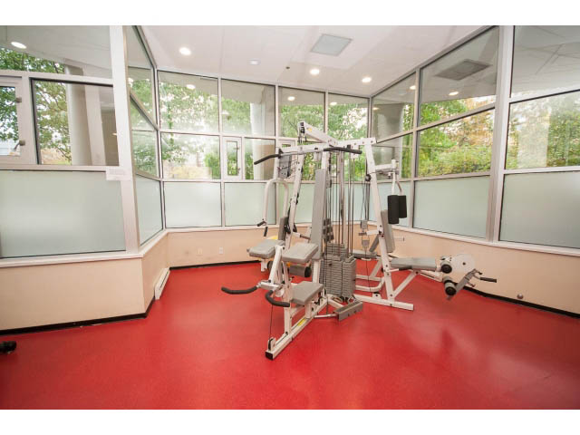 Spacious gym with red flooring and large windows, featuring exercise equipment. - 202 - 1277 Nelson St, Vancouver Downtown