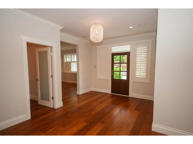 Bright dining area with hardwood floors and large windows, leading to a kitchen. - 3476 Wellington Crescent, North Vancouver