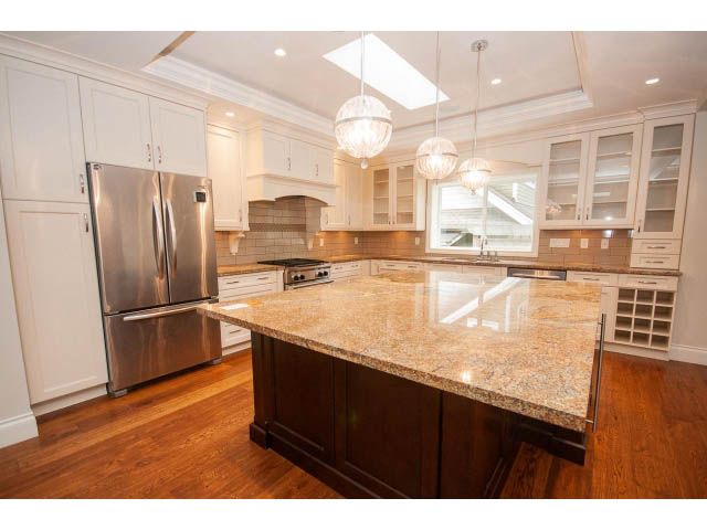 Bright kitchen with granite countertops, hardwood floors, and a stainless steel refrigerator. - 3476 Wellington Crescent, North Vancouver