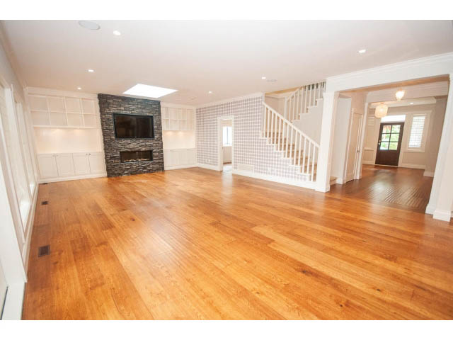 Bright open-concept living room with hardwood floors and white staircase leading to upper level. - 3476 Wellington Crescent, North Vancouver