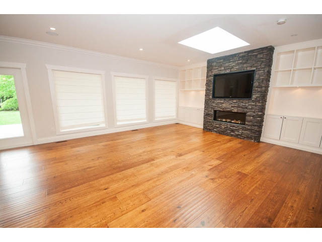 Bright living room with hardwood floors, built-in shelves, and a stone fireplace. - 3476 Wellington Crescent, North Vancouver