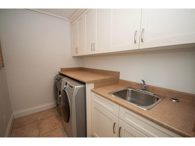 Bright laundry room with granite countertops and white cabinets. - 3476 Wellington Crescent, North Vancouver