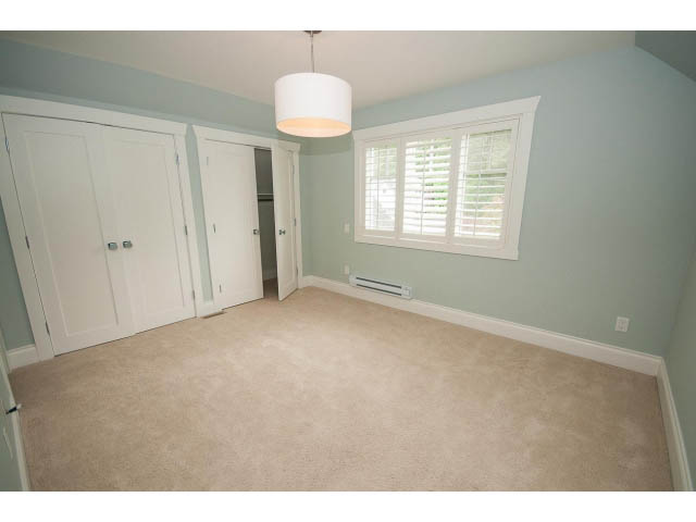 Spacious bedroom with light blue walls, white closet doors, and a window with white blinds. - 3476 Wellington Crescent, North Vancouver