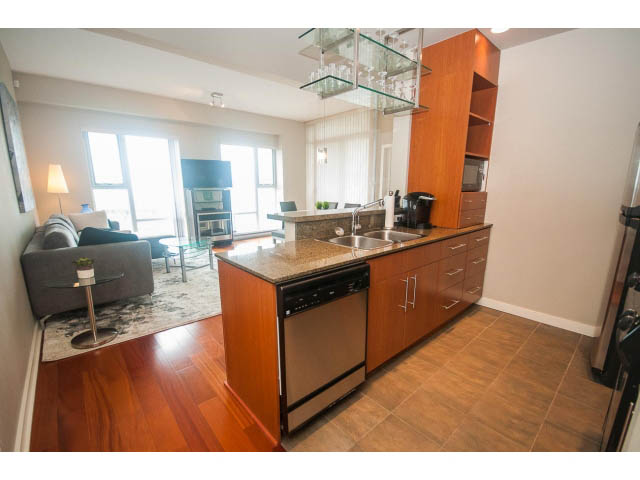 Bright kitchen with granite countertops and hardwood floors, open to a cozy living area with city views.