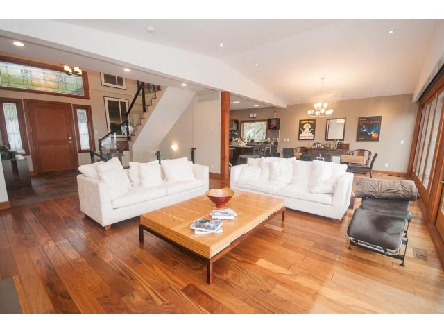 Spacious living room with hardwood floors, white furniture, and a staircase leading up. - Upper - 4407 Prospect Rd, North Vancouver
