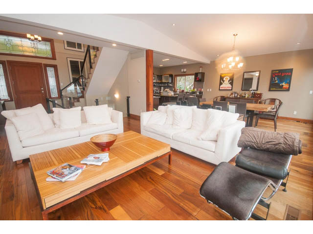Spacious living room with hardwood floors, white couches, and a wooden coffee table. - Upper - 4407 Prospect Rd, North Vancouver