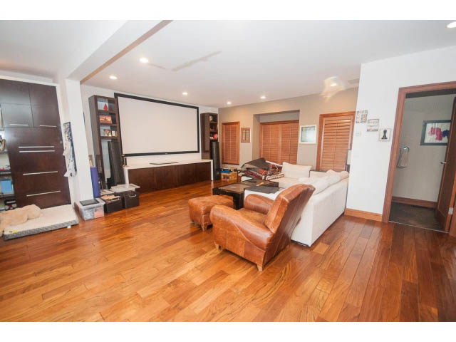 Spacious living room with hardwood floors, leather furniture, and a large screen TV. - Upper - 4407 Prospect Rd, North Vancouver