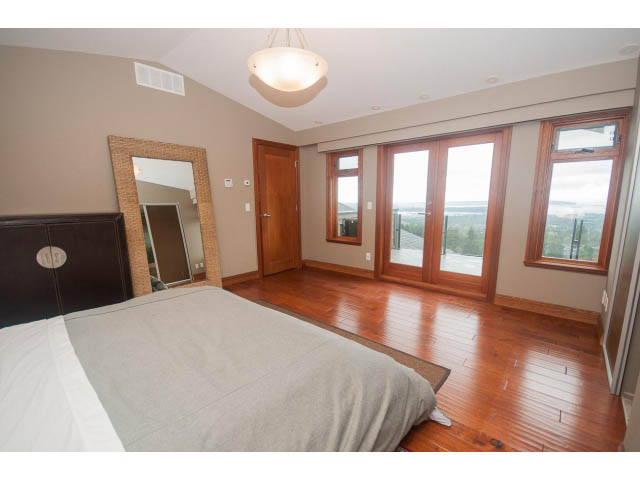 Spacious bedroom with hardwood floors, large windows, and a city view. - Upper - 4407 Prospect Rd, North Vancouver