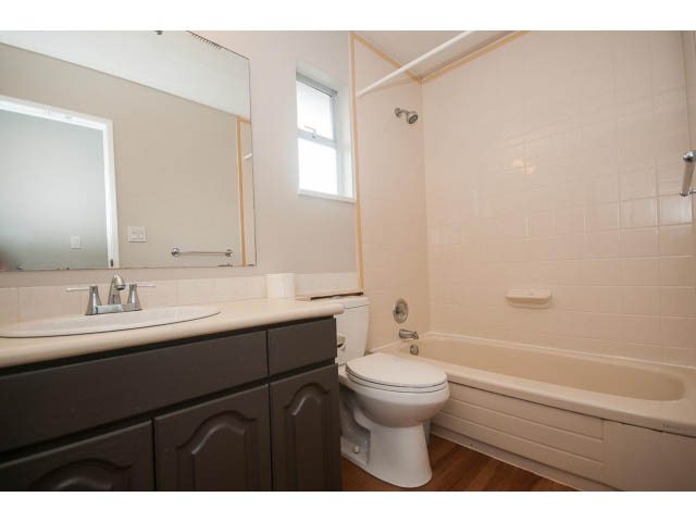 Bright bathroom with white tiles, dark vanity, and wooden floor. - Upper - 113 W Kings Rd, North Vancouver