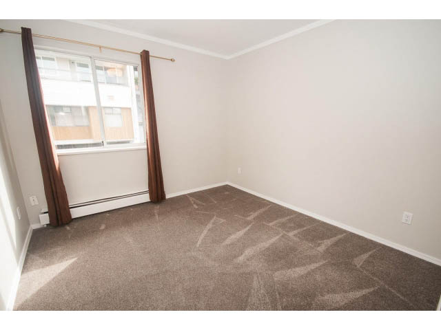 Bright living room with carpeted floors and a large window showing a city view. - Upper - 113 W Kings Rd, North Vancouver