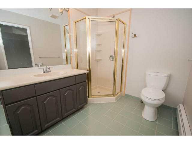 Bright bathroom with dark cabinets, white fixtures, and teal tile flooring. - Upper - 113 W Kings Rd, North Vancouver