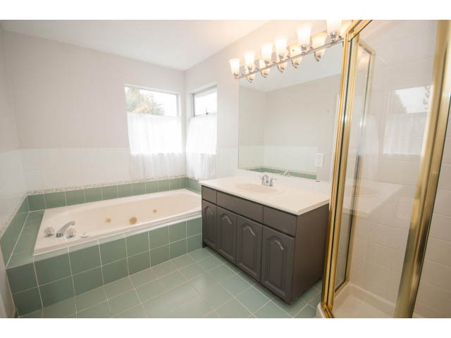 Spacious bathroom with green tiles, white countertop, and large mirror. - Upper - 113 W Kings Rd, North Vancouver