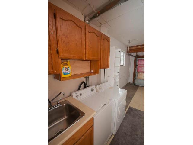 Bright kitchen with wooden cabinets, stainless steel sink, and laundry area. - Upper - 113 W Kings Rd, North Vancouver