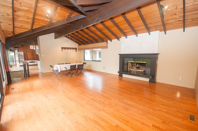 Spacious living room with hardwood floors, exposed beams, and a fireplace. - 4645 Caulfeild Drive, West Vancouver