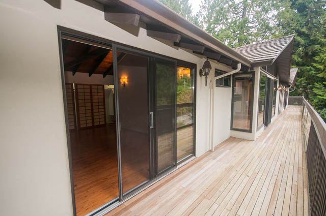 Furnished living room with sliding glass doors and wooden deck. - 4645 Caulfeild Drive, West Vancouver