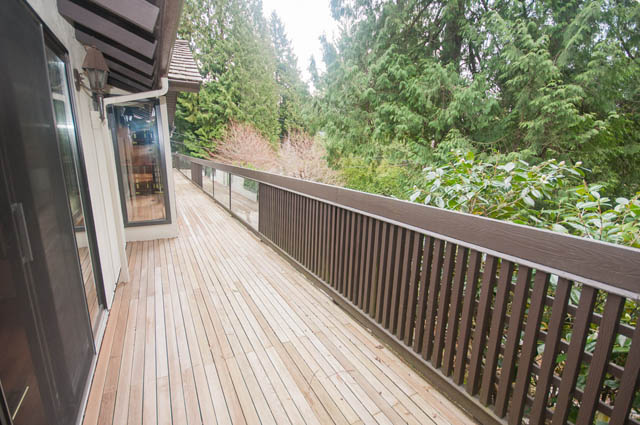 Furnished deck with wooden flooring and railings, surrounded by lush greenery. - 4645 Caulfeild Drive, West Vancouver