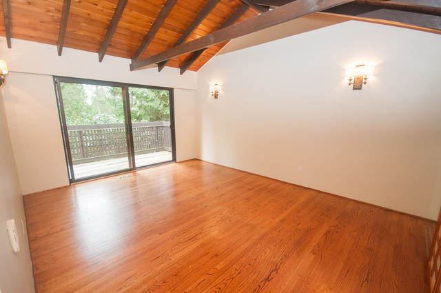Bright living room with hardwood floors and large sliding glass door leading to a deck. - 4645 Caulfeild Drive, West Vancouver