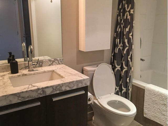 Bathroom with marble countertops and a modern shower curtain. - 1802 - 1351 Continental St., Vancouver Downtown