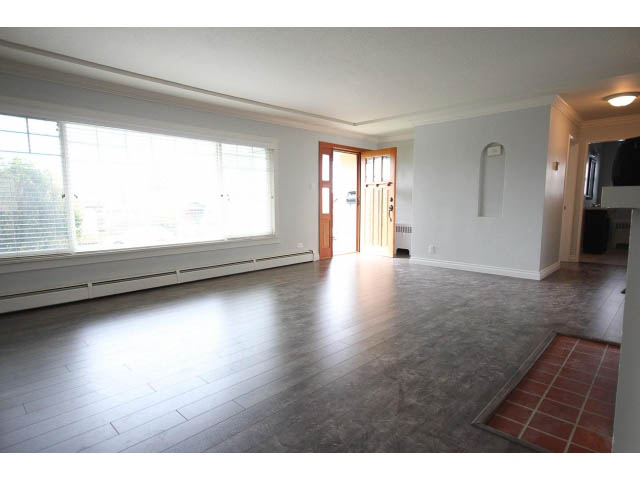 Spacious living room with hardwood floors and large windows. - 618 7th Street East, North Vancouver