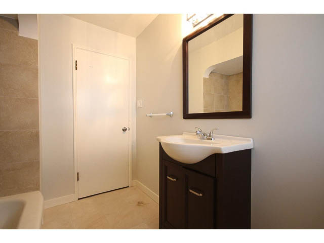 Bright bathroom with white sink, dark wood cabinets, and large mirror. - 618 7th Street East, North Vancouver