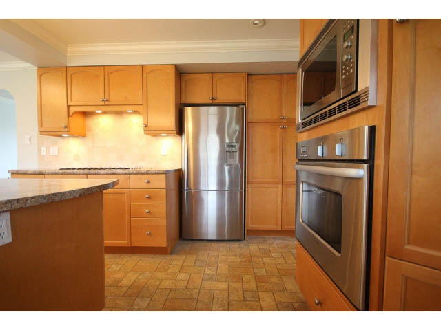 Bright kitchen with granite countertops, stainless steel appliances, and wooden cabinetry. - 618 7th Street East, North Vancouver