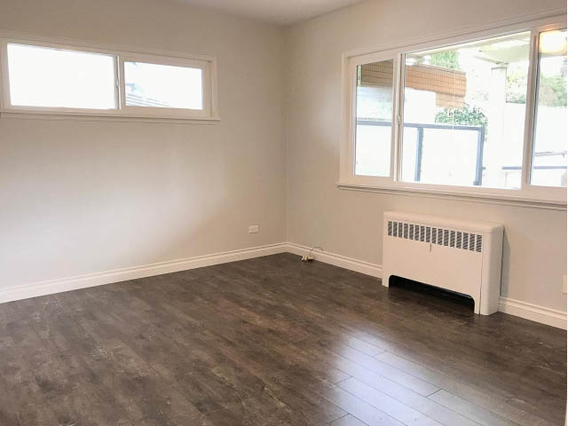 Bright living room with hardwood floors and large windows. - 618 7th Street East, North Vancouver
