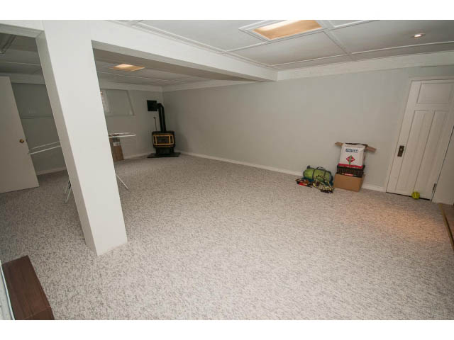 Living room with white walls, hardwood floors, and a wood-burning stove. - 618 7th Street East, North Vancouver