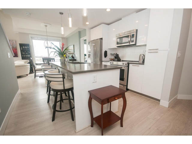 Bright kitchen with white cabinets, hardwood floors, and a city view. - 624 - 723 W 3rd St, North Vancouver