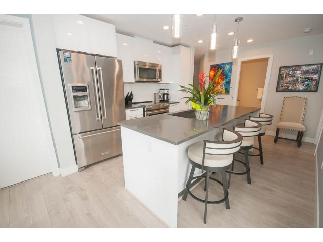 Bright kitchen with stainless steel appliances and white countertops, hardwood floors, and a city view. - 624 - 723 W 3rd St, North Vancouver