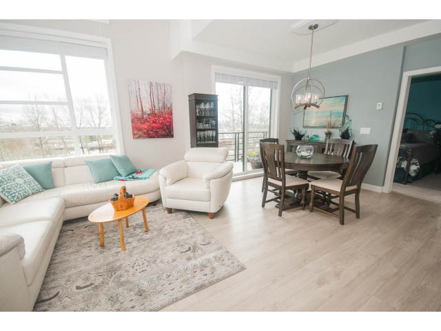 Spacious living room with hardwood floors, large windows, and a cozy sectional sofa. - 624 - 723 W 3rd St, North Vancouver