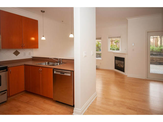 Bright kitchen with wooden cabinets, stainless steel appliances, and hardwood floors. - 104 - 128 West 21st St, North Vancouver