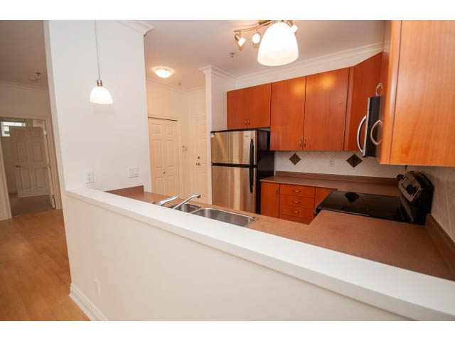 Bright kitchen with white countertops, hardwood floors, and a city view. - 104 - 128 West 21st St, North Vancouver
