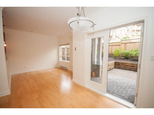 Bright living room with hardwood floors and sliding glass door leading to patio. - 104 - 128 West 21st St, North Vancouver