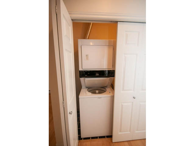 Bright laundry room with white appliances and hardwood floors. - 104 - 128 West 21st St, North Vancouver