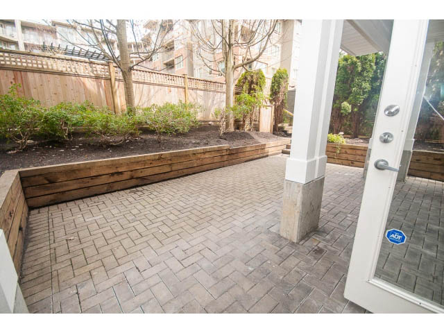 Furnished patio with brick flooring and wooden bench seating. - 104 - 128 West 21st St, North Vancouver