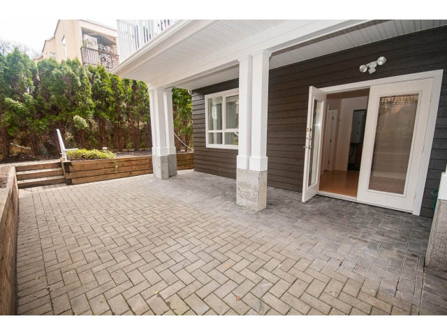 Furnished patio with brick pavers and sliding glass door leading inside. - 104 - 128 West 21st St, North Vancouver