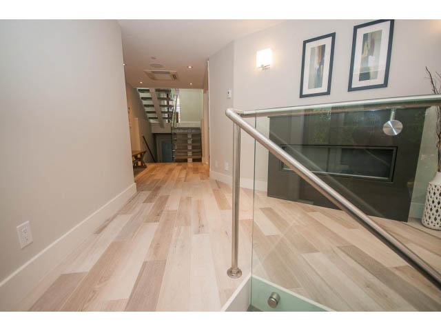 Bright hallway with glass railings and hardwood floors. - 2309 Bellevue Ave, West Vancouver