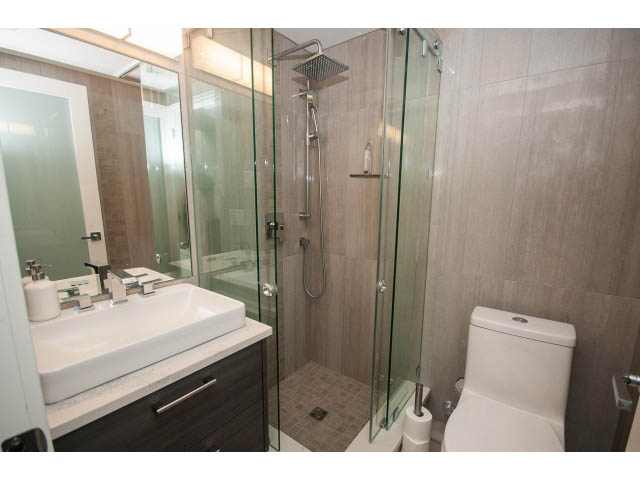 Modern bathroom with glass shower, granite countertops, and a sleek sink. - 2309 Bellevue Ave, West Vancouver