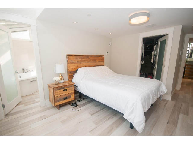 Spacious bedroom with hardwood floors, wooden headboard, and closet access. - 2309 Bellevue Ave, West Vancouver