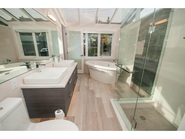 Bright bathroom with modern vanity, hardwood floors, and glass shower enclosure. - 2309 Bellevue Ave, West Vancouver