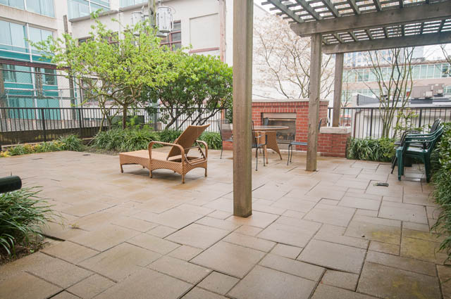 Furnished patio with outdoor seating, brick fireplace, and urban view. - 403 - 531 Beatty St, Vancouver Downtown