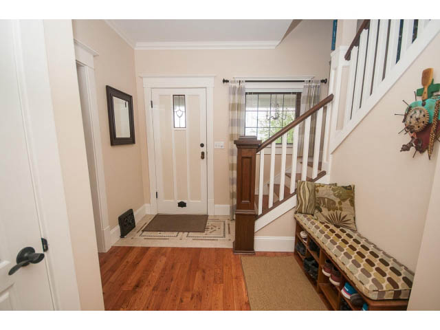 Foyer with hardwood floors, staircase, and decorative bench. - 266 W 6th St, North Vancouver