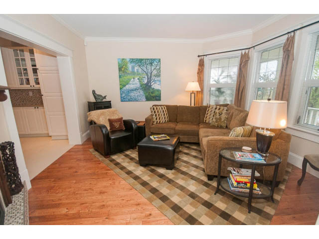 Furnished living room with hardwood floors, checkered rug, and large windows. - 266 W 6th St, North Vancouver