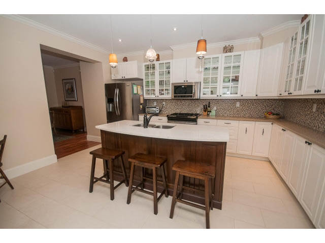 Bright kitchen with white cabinets, dark wood bar stools, and a city view. - 266 W 6th St, North Vancouver