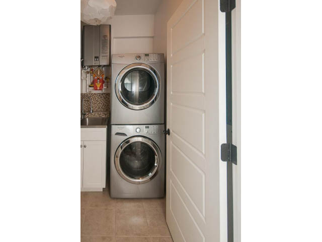 Bright laundry room with white cabinets and stainless steel appliances. - 266 W 6th St, North Vancouver