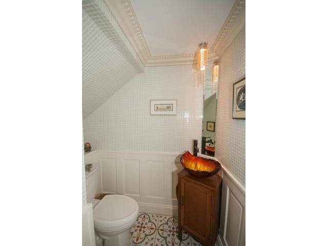 Bright bathroom with white tile, wooden cabinet, and decorative light fixture. - 266 W 6th St, North Vancouver